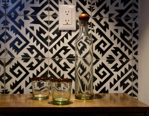 una botella y dos vasos en una mesa con una pared en Casa Irake en Guadalajara