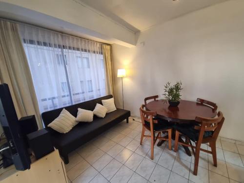 ein Wohnzimmer mit einem schwarzen Sofa und einem Tisch in der Unterkunft Departamento juan martines in Iquique