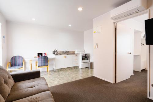 a living room with a couch and a kitchen at Highway Lodge Motel in Balclutha