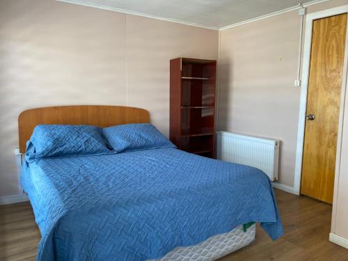 um quarto com uma cama com um edredão azul em World's End Hostal em Puerto Natales