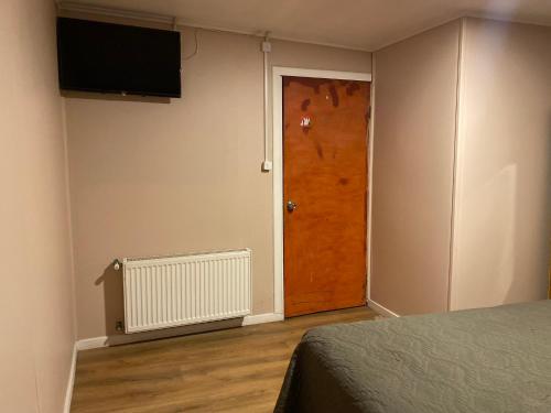 um quarto com uma porta castanha e uma televisão em World's End Hostal em Puerto Natales