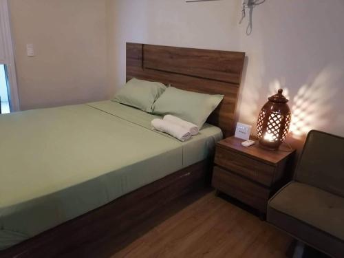 een slaapkamer met een bed, een lamp en een stoel bij Celadon Tower- Studio with balcony near SM San Lazaro in Manilla