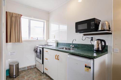 a small kitchen with a sink and a microwave at Highway Lodge Motel in Balclutha