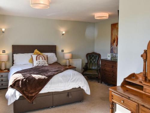 a bedroom with a large bed and a chair at Arun Cottage in Loxwood