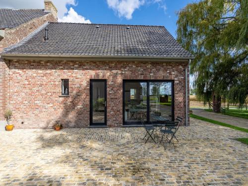a brick house with black windows and a patio at Holiday Home with pond in Poperinge in Beveren