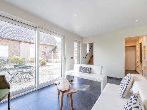 a living room with a couch and a large window at Holiday Home with pond in Poperinge in Beveren