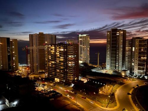una ciudad iluminada por la noche con edificios y tráfico en Costa de Montemar en Concón