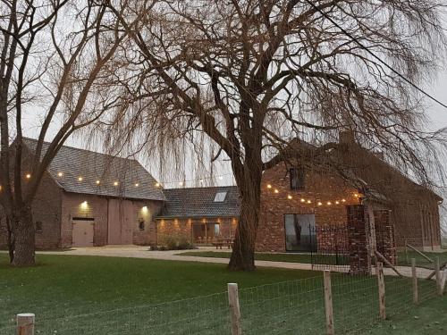 a brick house with a tree and a fence at Holiday Home with pond in Poperinge in Beveren