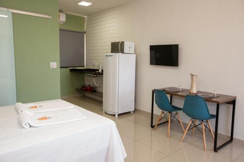 a room with a white refrigerator and a table and chairs at Jahu Center Plaza Flats in Jaú
