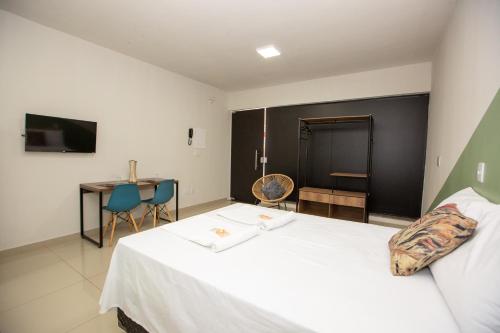a bedroom with a bed and a table and a desk at Jahu Center Plaza Flats in Jaú