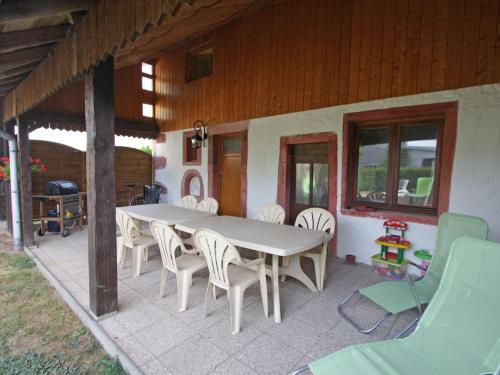 une table et des chaises sur le patio d'une maison dans l'établissement Gîte authentique avec terrasse couverte, 16 km de Gérardmer, 4 chambres, équipement bébé, Wi-Fi inclus - FR-1-589-231, à Aumontzey