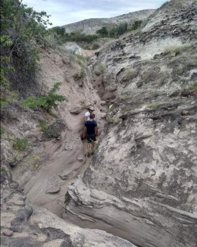 two people walking down a rocky mountain path at Mirador Valle de la Tatacoa in Villavieja