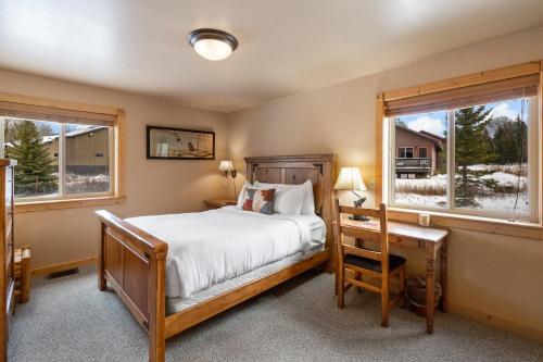 a bedroom with a bed and a desk and two windows at Mule Deer Cabin in West Yellowstone