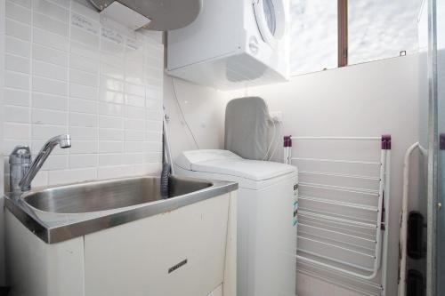 Una pequeña cocina con fregadero y lavadora. en Bellevue, 7 4 Donald Street - renovated unit with air con and Wi-Fi with views & central to CBD, en Nelson Bay