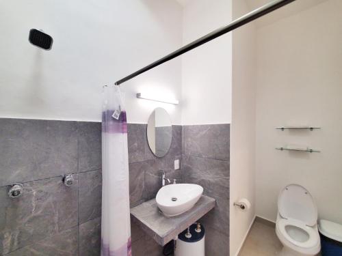 een badkamer met een wastafel, een toilet en een spiegel bij Quinta Suites in Cozumel