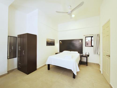 a bedroom with a white bed and a black cabinet at Quinta Suites in Cozumel