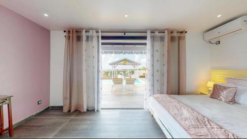 - une chambre avec un lit et une vue sur une terrasse dans l'établissement La Baie des Bambous SFX, à Saint-François