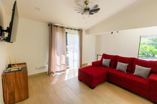 sala de estar con sofá rojo y ventana en Casa del Bosque at La Fortuna, en Fortuna
