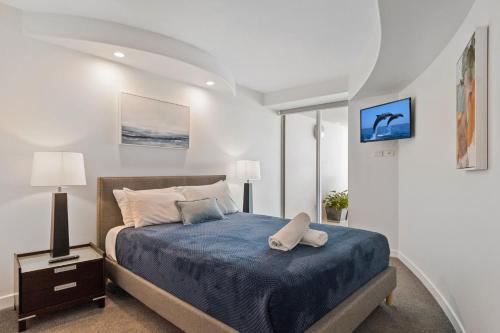 a bedroom with a blue bed with two pillows at Sirocco 906 in Mooloolaba