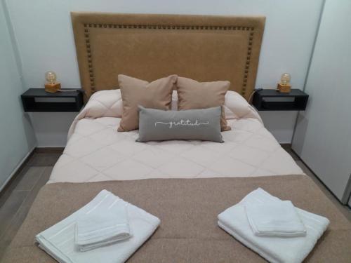 Una cama con dos toallas blancas encima. en Alquiler temporario en Tandil