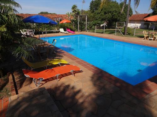 a swimming pool with a chair and an umbrella at Hotel Alto da Boa Vista in Analândia