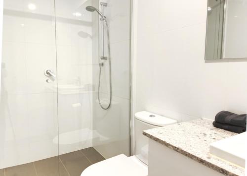 Pearl On Pakenham- Modern & Central W King Beds في فريمانتل: حمام أبيض مع دش ومرحاض