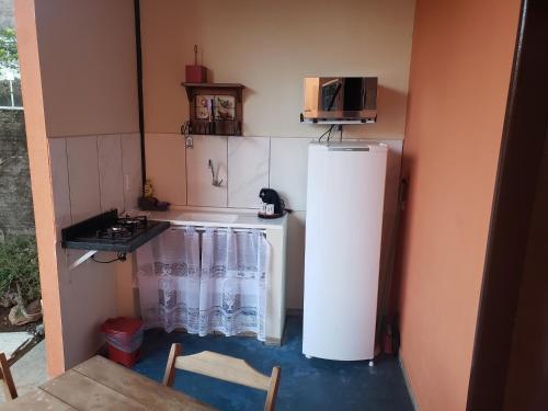 a small kitchen with a refrigerator and a stove at Chalés Flor de Manacá in Alto Paraíso de Goiás