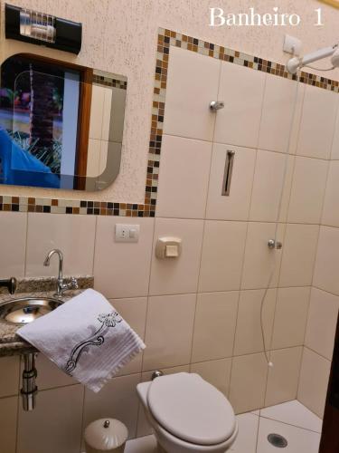 a bathroom with a toilet and a sink and a mirror at Este*Lar in Olímpia