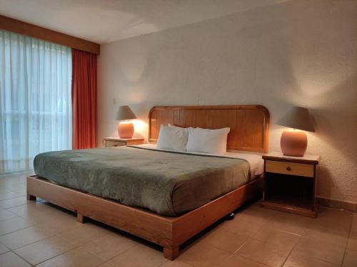 a bedroom with a large bed with two lamps on tables at Hotel La Rinconada Tequisquiapan in Tequisquiapan