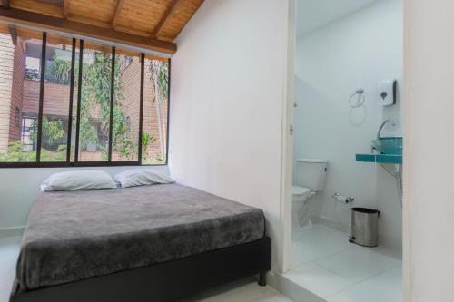 a bedroom with a bed and a window and a bathroom at Living Hotel in Medellín