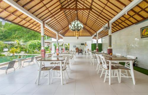 Kesari Glory Nusa Penida by Pramana Villas في نوسا بينيدا: مطعم بطاولات وكراسي ومسبح