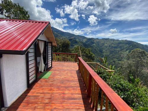 a wooden walkway leading to a building with a red roof at Glamping Akaya in Ibagué