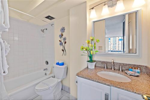 Un baño con lavabo, inodoro y espejo. en Pacific Monarch - 1 BR - Ocean and City Views!, en Honolulu