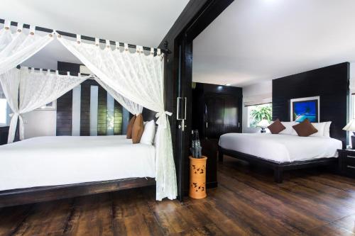 チャウエンにあるChaweng Cove Beach Resortのウッドフロアのベッドルーム(ベッド2台付)