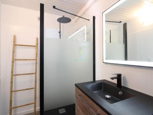 La salle de bains est pourvue d'un lavabo noir et d'un miroir. dans l'établissement Maison La Bourboule, 5 pièces, 9 personnes - FR-1-608-237, à La Bourboule