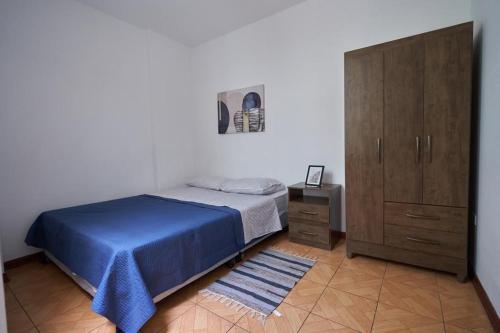 a bedroom with a blue bed and a wooden cabinet at A 3 Cdras del Centro histórico, Amplio y en Piso 2 in Trujillo