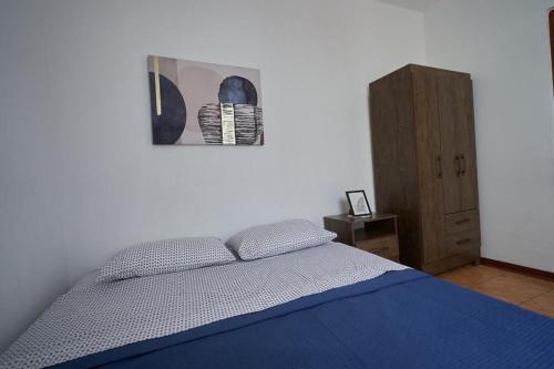 a bedroom with a blue bed and a wooden cabinet at A 3 Cdras del Centro histórico, Amplio y en Piso 2 in Trujillo