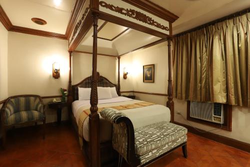 a bedroom with a canopy bed and a chair at Camelot Hotel in Manila