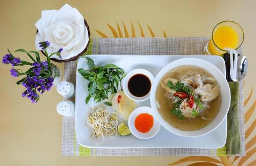 a plate of food with a bowl of soup and flowers at Côn Sơn Victory Hotel in Con Dao