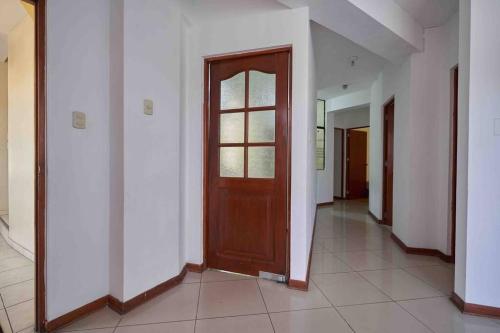 a hallway with a wooden door and white walls at A 3 Cdras del Centro histórico, Amplio y en Piso 2 in Trujillo