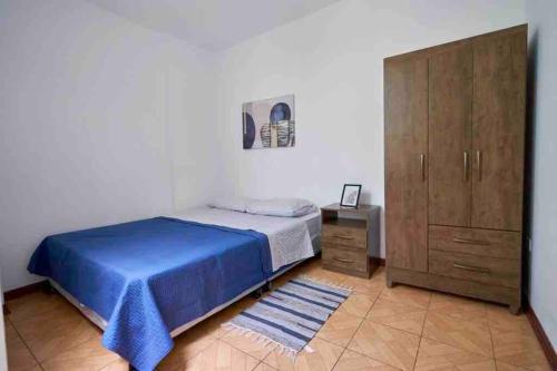 a bedroom with a blue bed and a wooden cabinet at A 3 Cdras del Centro histórico, Amplio y en Piso 2 in Trujillo