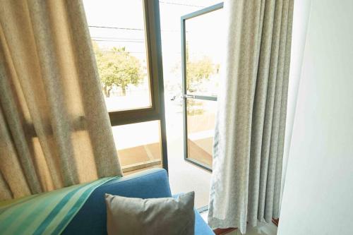 a room with a window with a blue couch and a window with curtains at A 3 Cdras del Centro histórico, Amplio y en Piso 2 in Trujillo