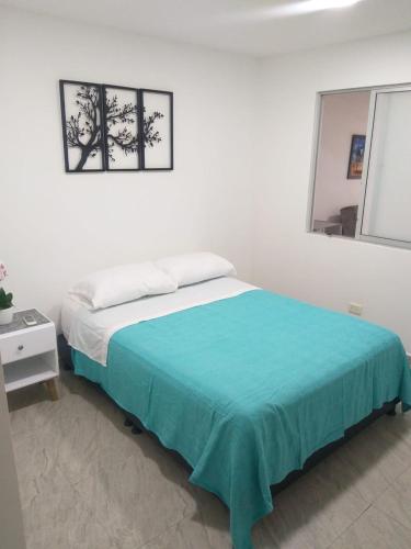 a white bedroom with a bed with a blue blanket at APARTA ESTUDIO CONDO in Villavicencio