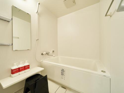 uma casa de banho branca com uma banheira e um espelho. em Rakuten STAY VILLA Awaji 106 3 bank beds, Capacity of 9 persons em Minamiawaji