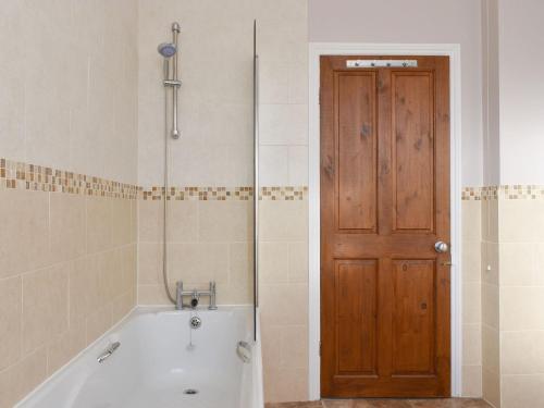 a bathroom with a tub and a wooden door at Number Five in Filey