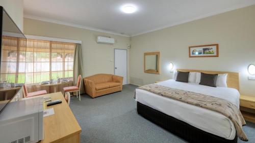 Habitación de hotel con cama, escritorio y TV. en Country Gardens Motor Inn, en Cowra