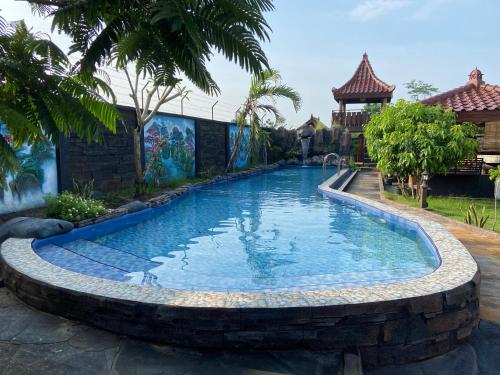 a swimming pool in a yard with a retaining wall at Villa Desa Pehkulon in Minggiran