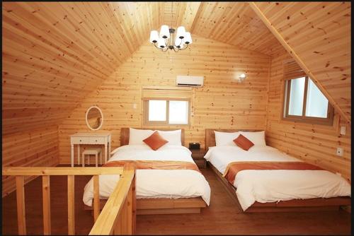 sypialnia z 2 łóżkami w drewnianym domku w obiekcie Zain Village w mieście Seogwipo