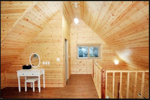 Cabaña de madera con mesa y espejo en Zain Village, en Seogwipo