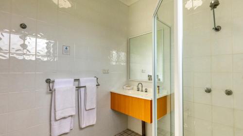 uma casa de banho branca com um lavatório e um chuveiro em Country Gardens Motor Inn em Cowra